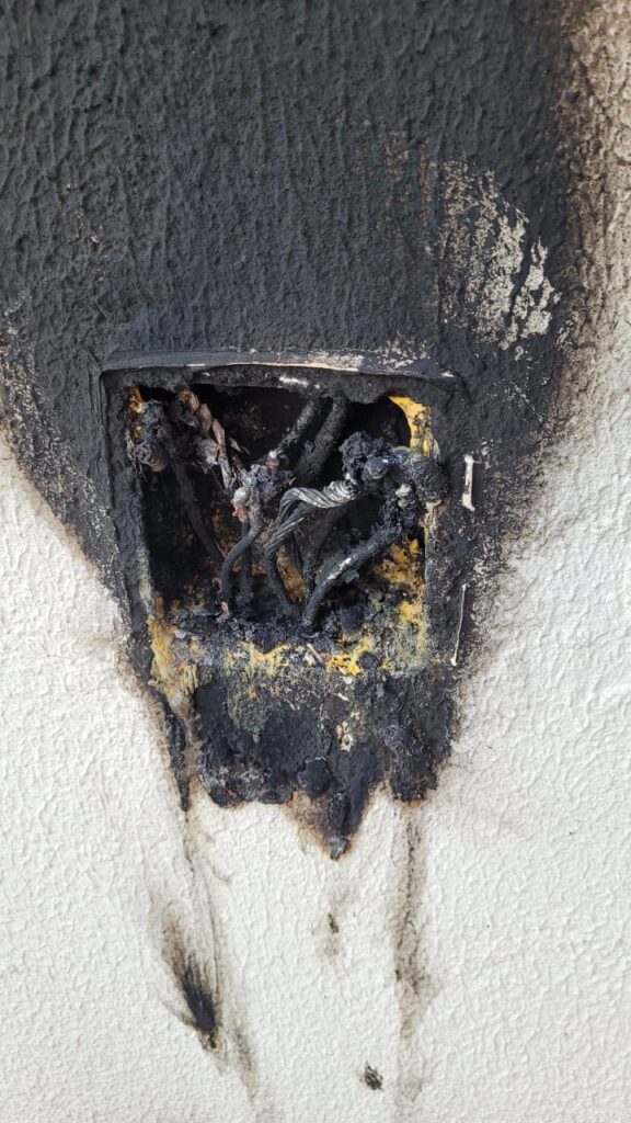 Curto-circuito em casa causado por fiação sobrecarregada dentro de uma caixa de passagem elétrica.