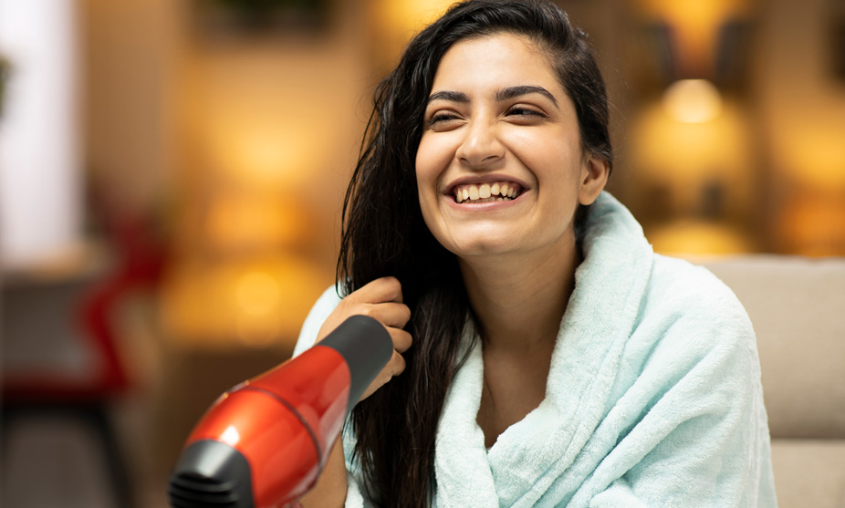 Mulher secando o cabelo molhado com secador de cabelo