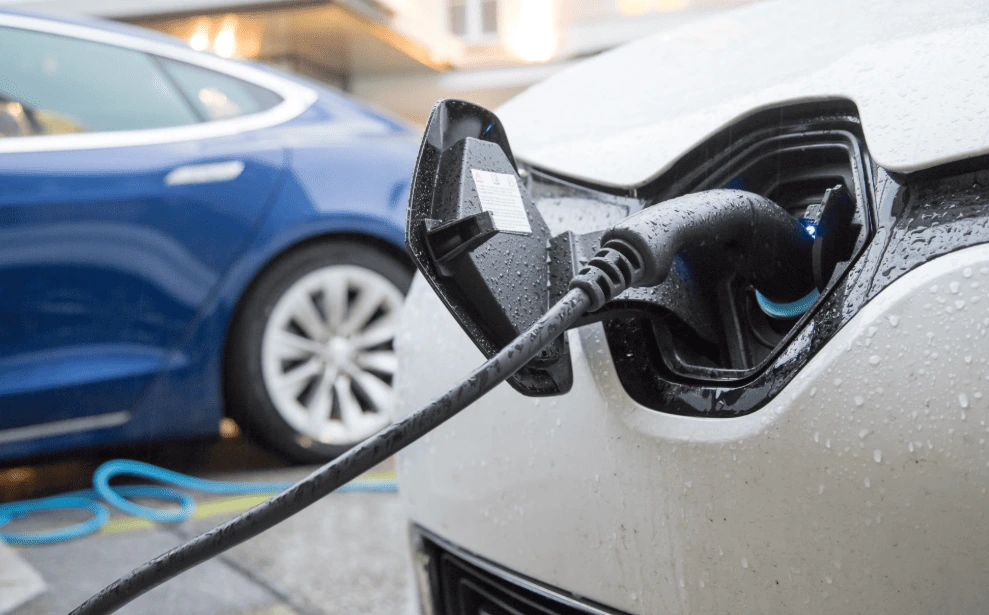 Dois carros elétricos carregando simultaneamente em tomadas residenciais com cuidados de segurança