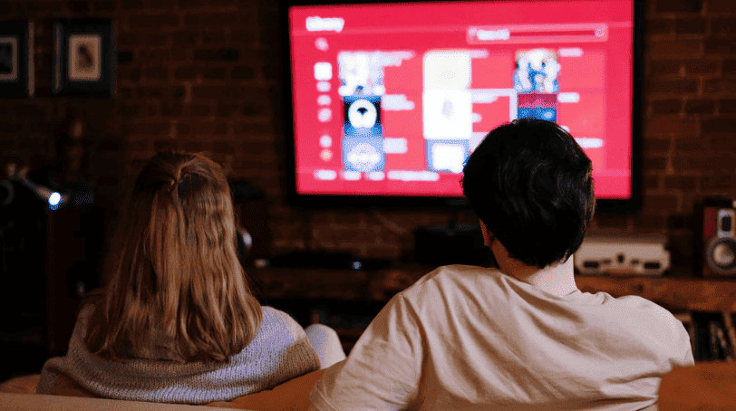 Família sentada no sofá assistindo TV durante horário de pico de consumo de energia