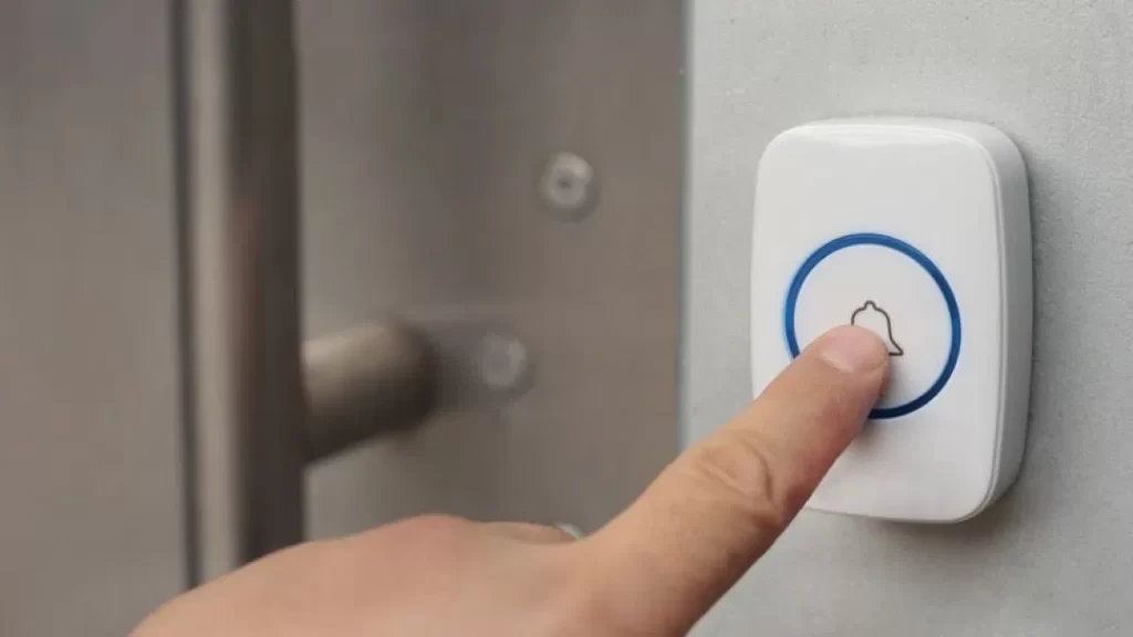 Pessoa tocando a campainha de uma casa com o dedo