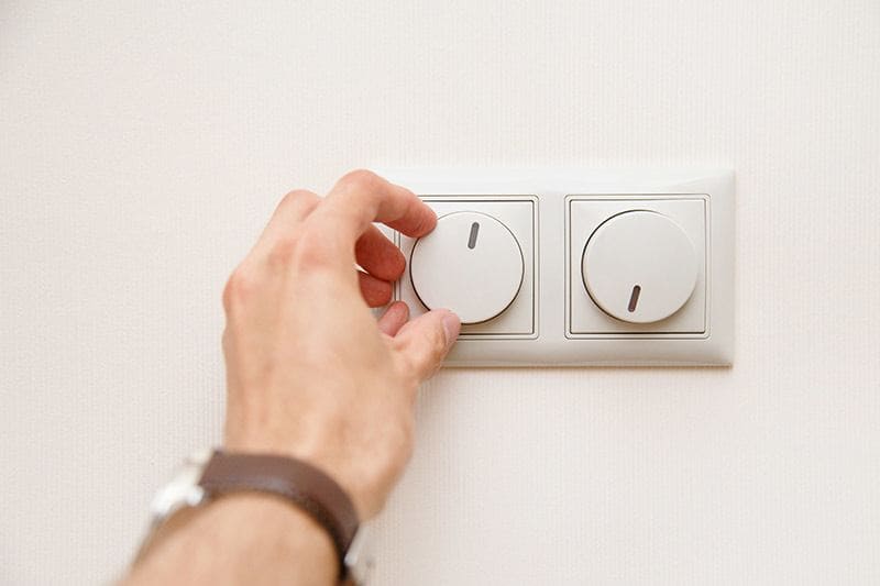 Mão ajustando o dimmer em interruptor de luz para controlar a intensidade