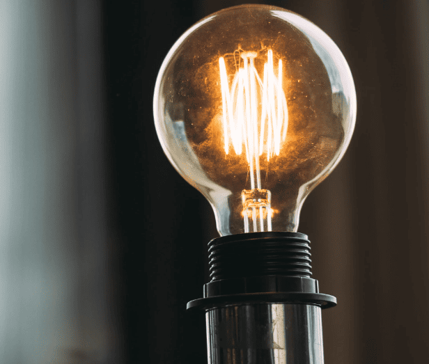 Lâmpada incandescente acesa em luminária, mostrando o filamento brilhando