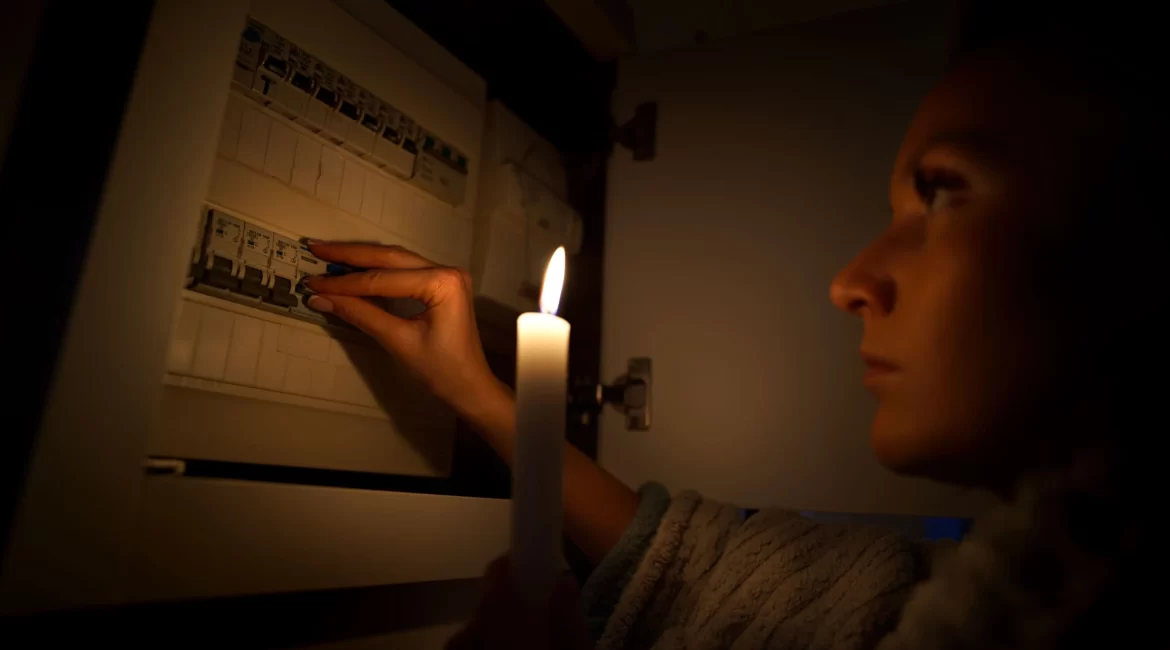 Mulher caminhando até o quadro de luz com uma vela durante uma queda de energia