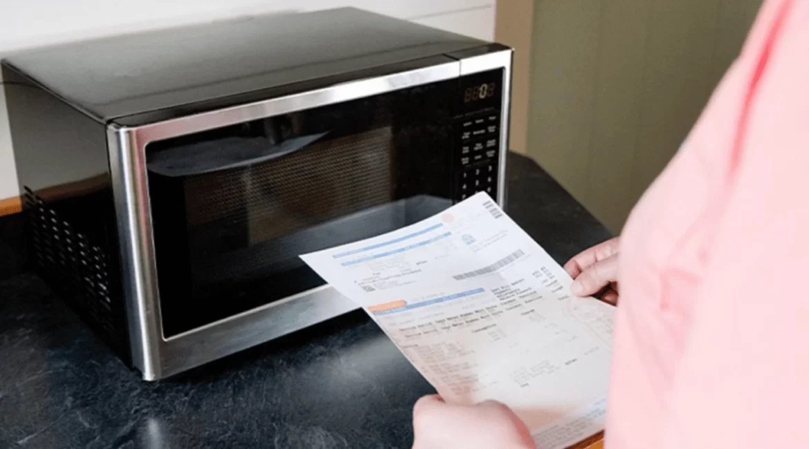 Pessoa segurando a conta de luz e olhando para o micro-ondas
