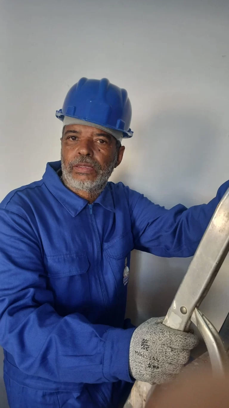 Seu Domingos Eletricista uniformizado subindo na escada para instalar plafons de LED em apartamento em São Paulo