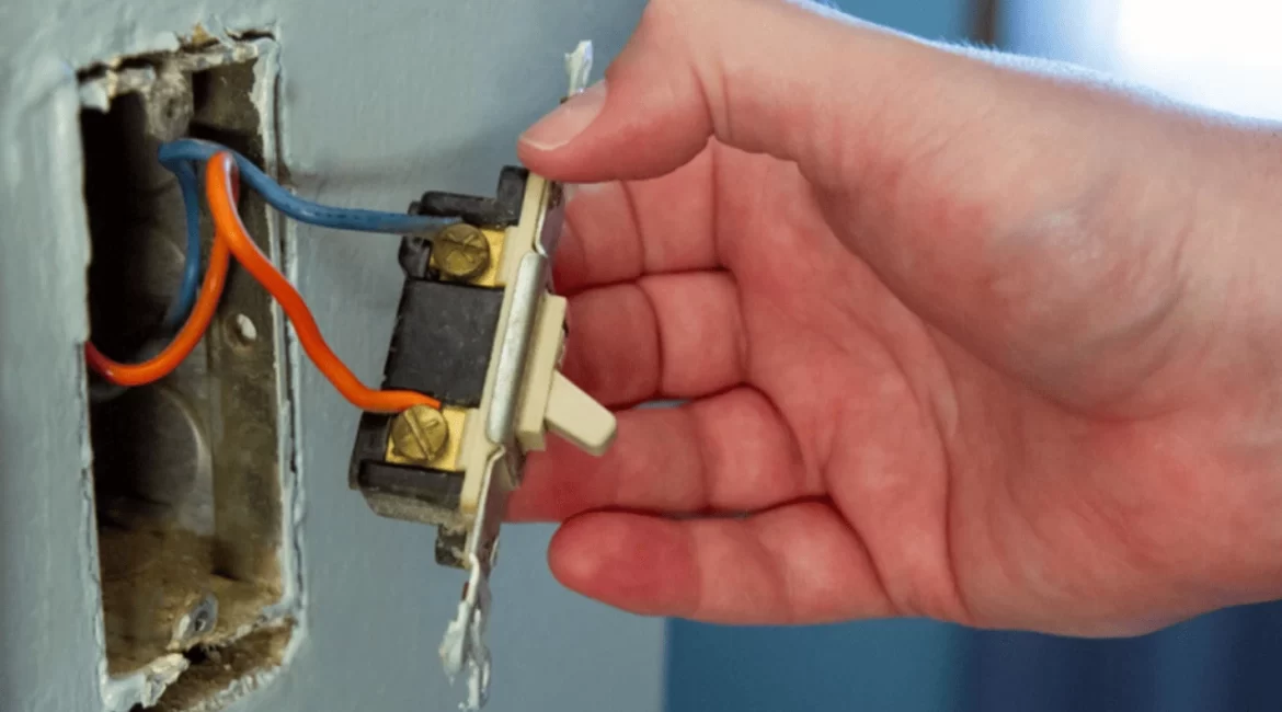 Mão realizando reparo em um interruptor de luz defeituoso
