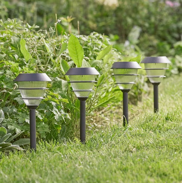 Duas luminárias solares iluminando um jardim bem cuidado