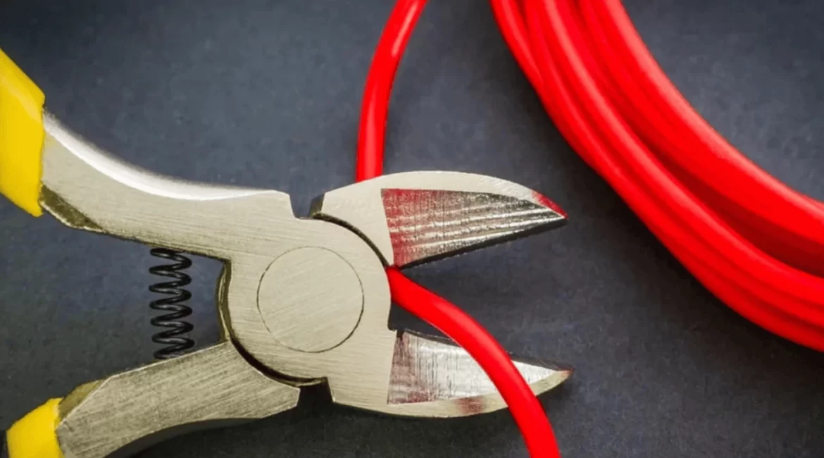 Alicate cortando fio elétrico durante correção de falhas na fiação