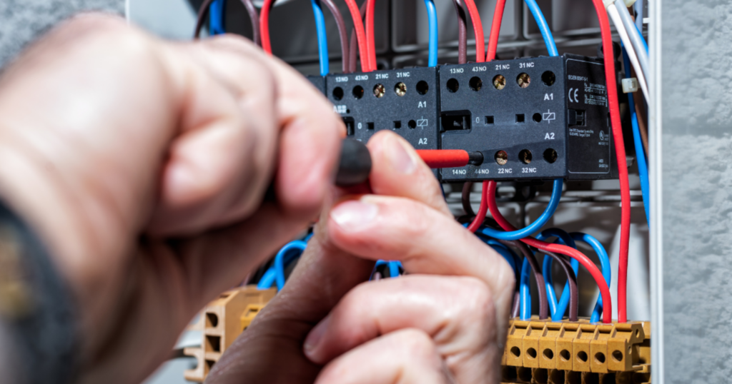 Eletricista conectando fios em quadro elétrico com chave de fenda
